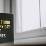 Rectangular shaped book with printed title on black hardcover on windowsill in house in daytime